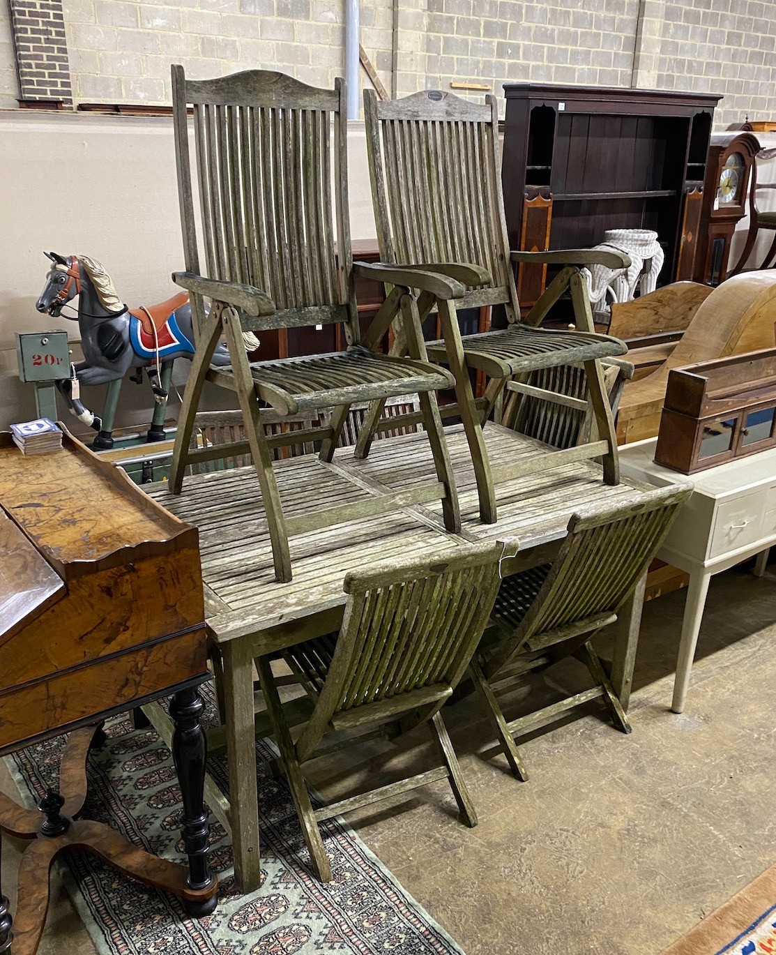 A rectangular weathered teak extending garden table, length 192cm extended, width 89cm, height 76cm together with eight teak folding garden chairs, two with arms